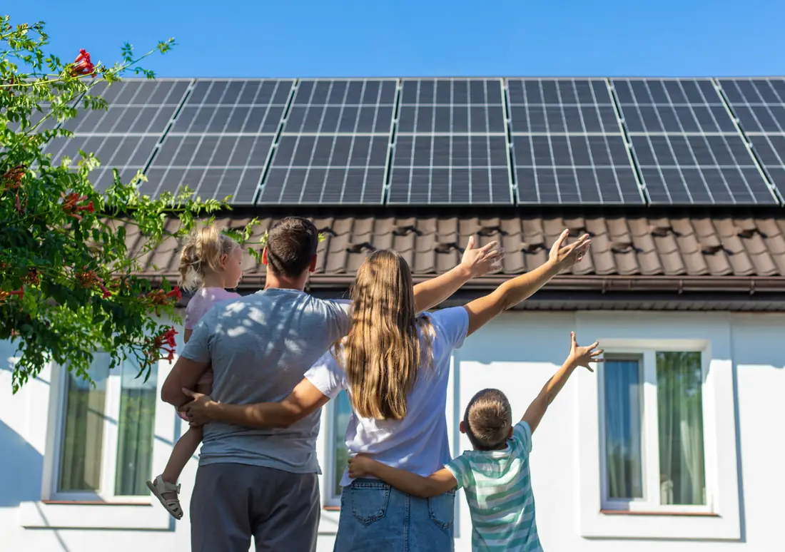 A family looking up at the solar panels on their roof