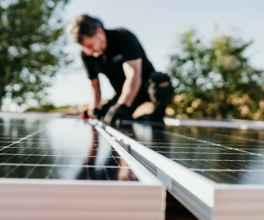 An installer fixing solar panels to their mounting rails